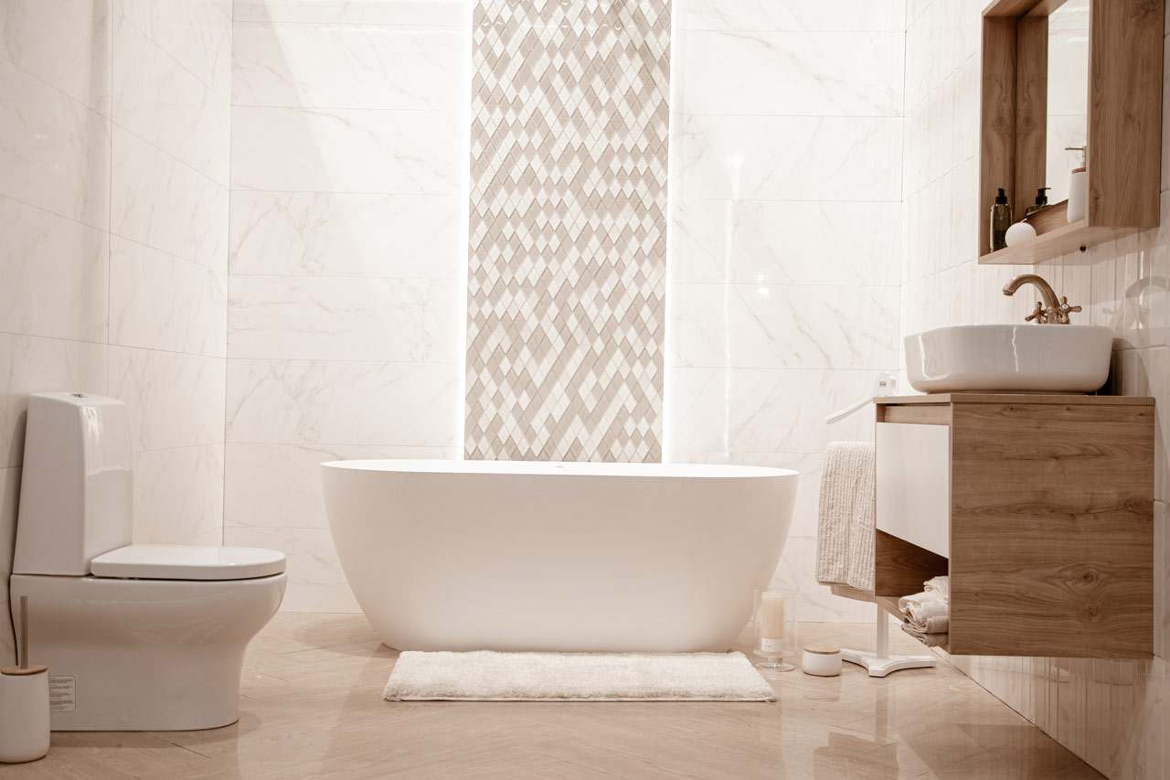 Luxurious bathroom featuring a standalone white bathtub against a backdrop of elegant marble tiles with a unique diamond pattern accent wall. The space is complemented by a wooden vanity with a vessel sink and matching wooden shelving, enhancing the spa-like atmosphere with natural textures and a calming neutral palette.