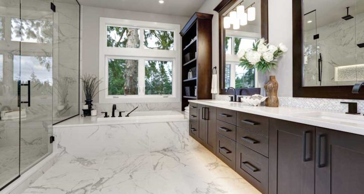 Elegant bathroom featuring a spacious layout with a glass-enclosed shower, a soaking tub, and a long vanity with dark wood cabinets and white marble countertops. Large windows allow natural light to flood the room, highlighting the beautiful marble floor and walls. Decorative elements like flowers and stylish lighting fixtures add to the luxurious ambiance.